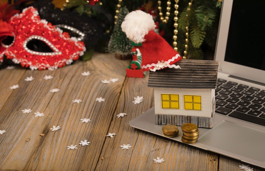 An Image of a small paper house with santa clause hat placed on a laptop