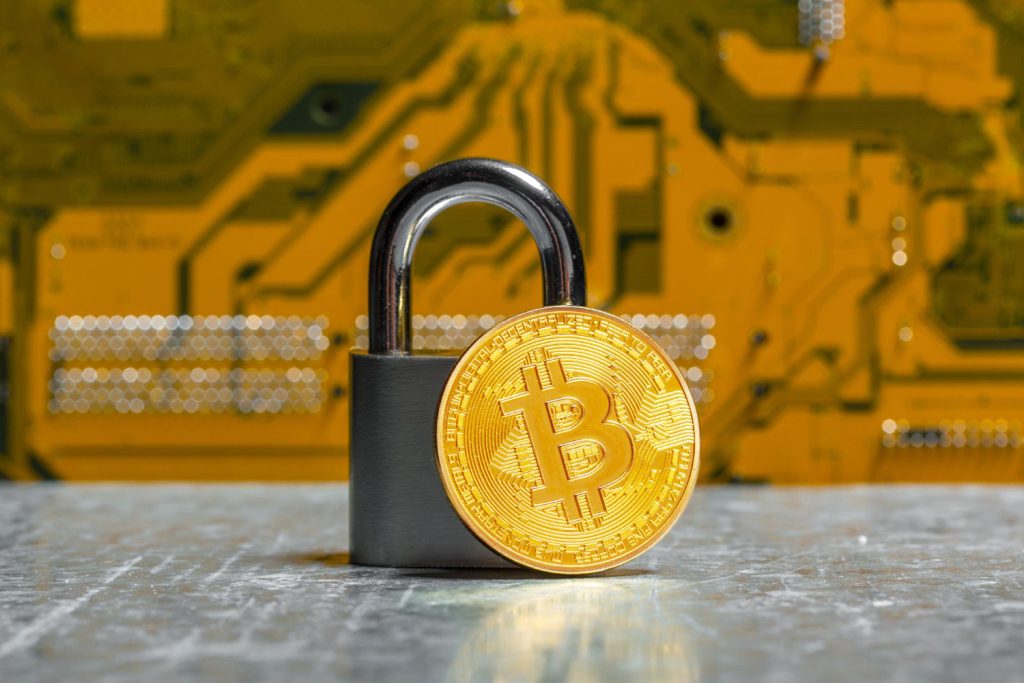 A gold Bitcoin placed beside a padlock, representing secure cryptocurrency storage and protection.