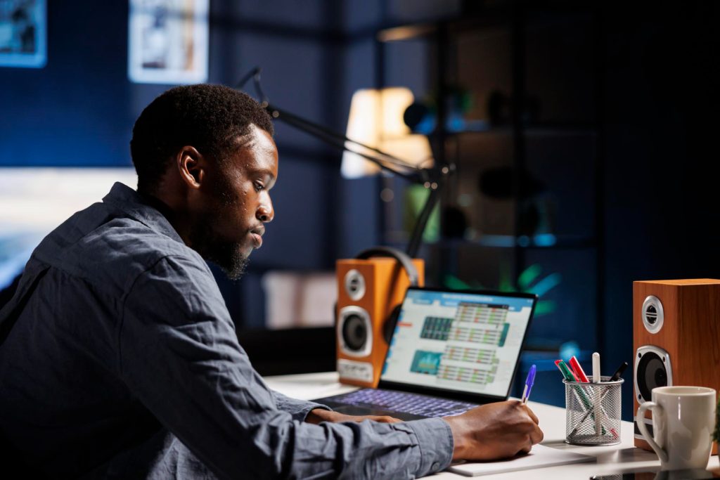 Black man analyzing cryptocurrency data on a laptop, symbolizing learning how crypto works and tracking digital asset transactions.