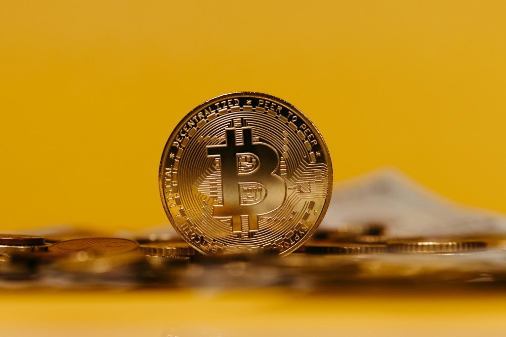 Close-up of a Bitcoin coin with a yellow background, representing cryptocurrency.
